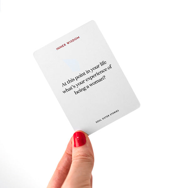 Hand holding a card. Text on card says; At this point in your life what's your experience of being a woman?