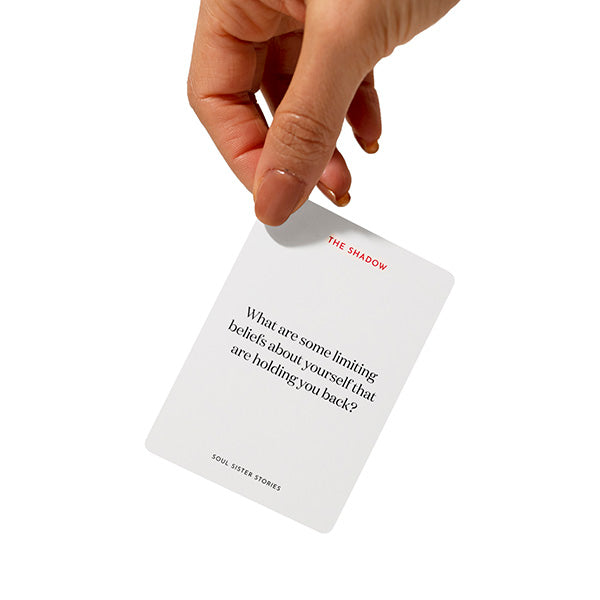 Hand holding a card. Text on card says What are some limiting beliefs about yourself that are holding you back?